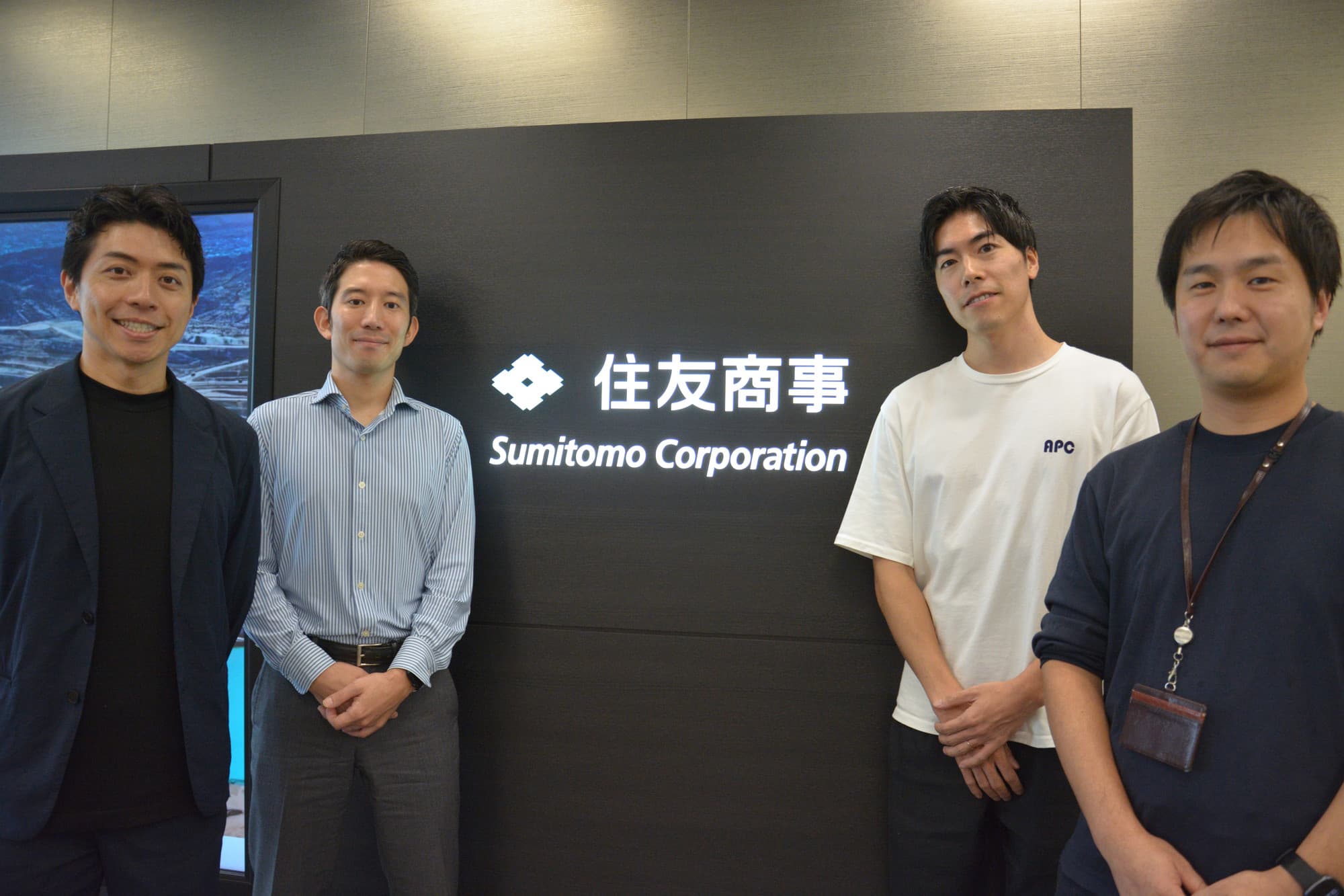 住友商事の看板前に並ぶ4名
